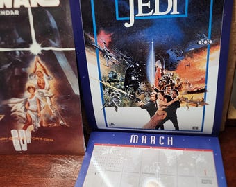 May include: A vintage Star Wars calendar featuring the movie poster for "Return of the Jedi" with the text "El Retorno del Jedi." The calendar is open to the month of March, with a Star Wars image. A Star Wars calendar is on the left.