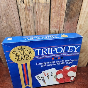 May include: A blue Tripoley game box with the text "Cadaco Senior Series" and "Tripoley". The box includes playing cards and red and white chips. The game is described as the original game of Michigan Rummy, Hearts & Poker.