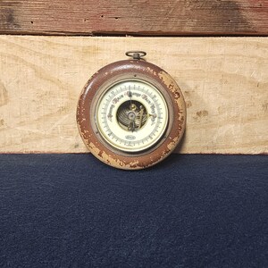 May include: A vintage wooden barometer with a white face and black markings. The face reads "Young Main" and "Range Hair Vert".