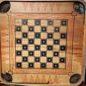 May include: A vintage wooden game board with a checkerboard pattern and orange and black accents. The board has a wooden frame and is surrounded by a rope border. The game includes wooden pieces, green and red plastic rings, and a wooden stick.