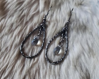 May include: A pair of dark gunmetal-toned earrings featuring a twisted wire teardrop frame. Each earring suspends a single, small, clear faceted crystal bead from the center of the loop, attached with a simple hook-style ear wire for hanging.