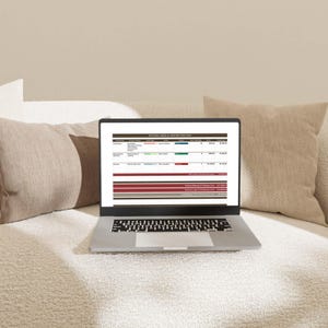 May include: A silver laptop displaying a spreadsheet titled Kitchen Labor & Contractor Cost. The screen shows columns for contractor, scope of work, item type, status, quantity, price, and total cost, with rows detailing various renovation expenses.