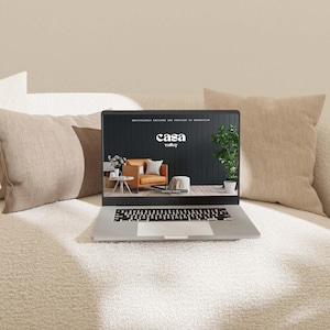Peut inclure: Un ordinateur portable ouvert sur un site web pour Casa Valley, une entreprise de meubles. Le site web présente un fond noir avec un logo blanc et une photo d'un fauteuil marron.
