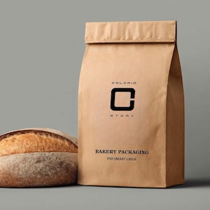 May include: A brown paper bag with the text "COLORID STORY" and "BAKERY PACKAGING" printed on it. A loaf of bread is visible on the left side of the image. The bag is folded at the top.