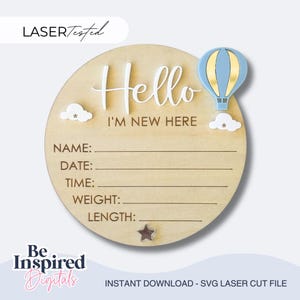 Puede incluir: Un letrero redondo de madera con las palabras "Hello I'm New Here". Presenta un globo aerostático azul y dorado, dos nubes blancas y espacio para escribir el nombre, la fecha, la hora, el peso y la longitud de un bebé. Una estrella está en la parte inferior.