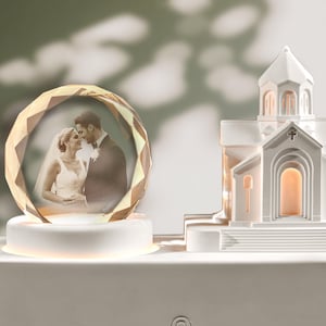 May include: A wedding-themed decorative light. It features a photo of a couple inside a faceted crystal orb, illuminated by a soft glow. A white church model is also present, enhancing the romantic atmosphere.
