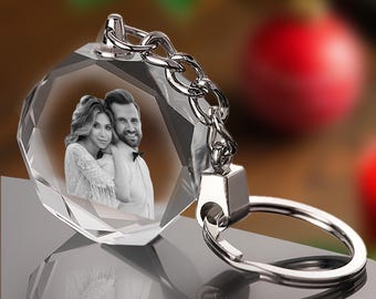 May include: A crystal keychain with a photo of a couple inside. The keychain is silver and has a clear crystal charm with a faceted design. The charm is about 2 inches in diameter.