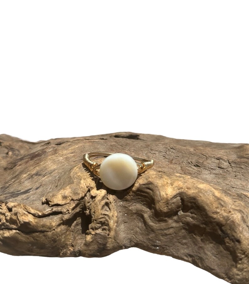 May include: A gold ring with a white round shell stone.