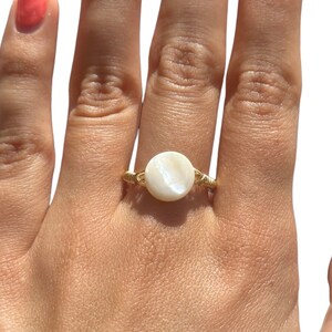 May include: A gold wire ring with a white mother of pearl stone.