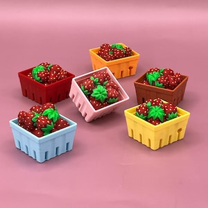 Puede incluir: Seis pequeñas cestas de bayas de colores llenas de fresas rojas con hojas verdes. Las cestas son rojas, naranjas, marrones, rosas, amarillas y azules. El fondo es rosa.