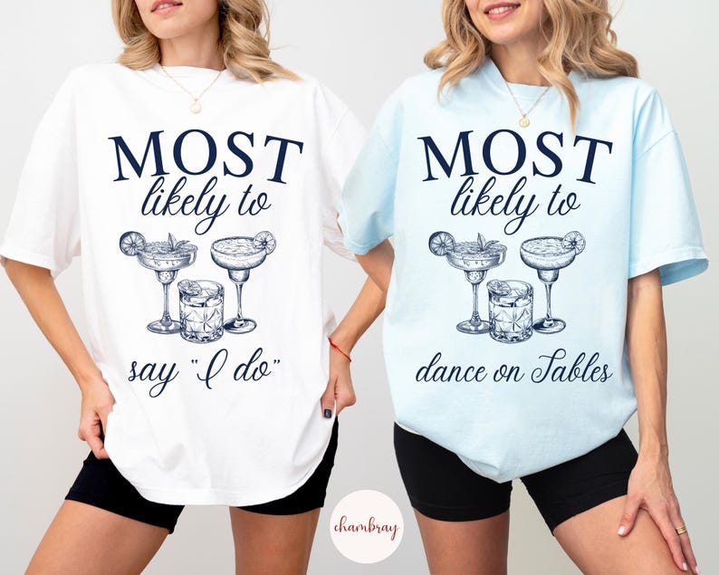 May include: Two white t-shirts with blue text and illustrations of cocktails. The text on the first shirt reads "MOST likely to say "I do"". The text on the second shirt reads "MOST likely to dance on tables".