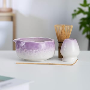 May include: A set of three ceramic mugs with a speckled, matte finish in cream, light grey, and dark grey. Each mug has a simple, minimalist design and a rounded handle.