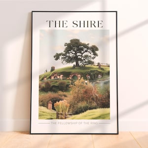 Puede incluir: Póster enmarcado que presenta una vista escénica de La Comarca de El Señor de los Anillos. La imagen muestra casas de hobbits construidas en una ladera verde, con un gran árbol en la cima. El texto en la parte superior dice "THE SHIRE" y en la inferior "THE FELLOWSHIP OF THE RING."