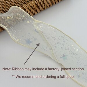 May include: Ivory ribbon with a star pattern. The ribbon has a wired edge and is decorated with various sizes of stars in silver and iridescent colors. The text on the image says, "Ribbon may include a factory-joined section."