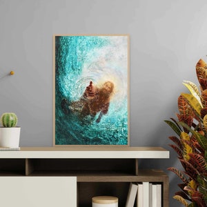 K&ouml;nnte beinhalten: Gerahmter Kunstdruck mit einer abstrakten Darstellung einer Figur im Wasser, in T&uuml;rkis, Braun und Gold. Das Kunstwerk hat eine strukturierte Optik und wird auf einem wei&szlig;en Regal mit dekorativen Pflanzen pr&auml;sentiert.