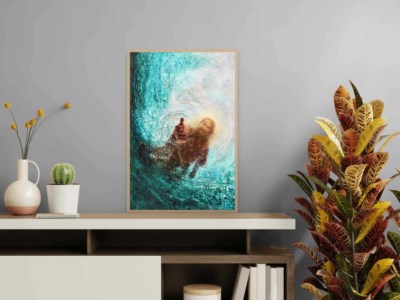 K&ouml;nnte beinhalten: Gerahmter Kunstdruck mit einer abstrakten Darstellung einer Figur im Wasser, in T&uuml;rkis, Braun und Gold. Das Kunstwerk hat eine strukturierte Optik und wird auf einem wei&szlig;en Regal mit dekorativen Pflanzen pr&auml;sentiert.