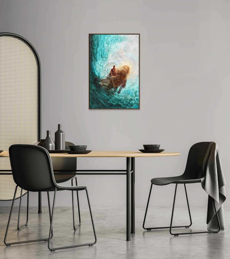 K&ouml;nnte beinhalten: Gerahmter Kunstdruck mit abstrakter Darstellung in T&uuml;rkis- und Braunt&ouml;nen. Das Kunstwerk zeigt eine Figur im Wasser mit hellem Licht dahinter. Der Druck h&auml;ngt &uuml;ber einem Holztisch mit schwarzen St&uuml;hlen.