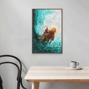 K&ouml;nnte beinhalten: Ein gerahmtes Kunstwerk zeigt eine Figur in einem wirbelnden t&uuml;rkisfarbenen und wei&szlig;en Hintergrund, mit einem warmen, goldenen Licht dahinter. Das Kunstwerk h&auml;ngt an einer wei&szlig;en Wand &uuml;ber einem Holztisch, mit einer Tasse und Untertasse.