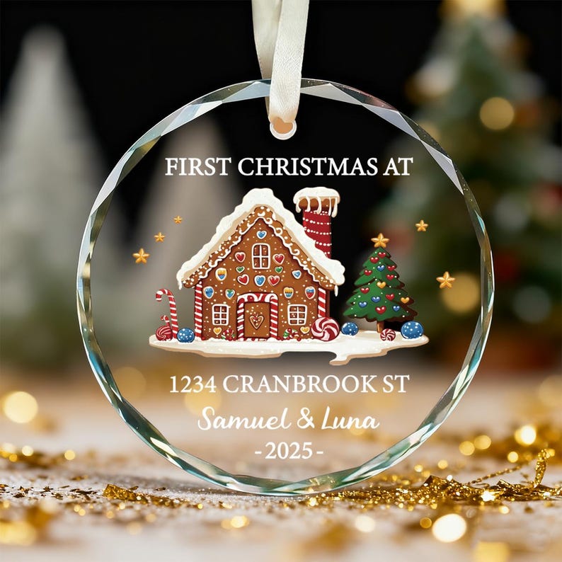 K&ouml;nnte beinhalten: Ein klarer, runder Weihnachtsschmuck mit einem Lebkuchenhaus-Design. Der Schmuck tr&auml;gt den Text "FIRST CHRISTMAS AT" oben, die Adresse "1234 CRANBROOK ST", die Namen "Samuel & Luna" und das Jahr "-2025-".