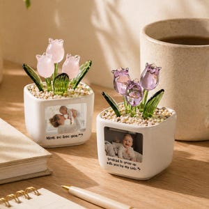 Puede incluir: Dos macetas de cerámica blanca con tulipanes de cristal y fotos. Una maceta tiene tulipanes rosas y el texto "Mom, we love you." La otra tiene tulipanes morados y el texto "Grateful to grow up with you by my side."