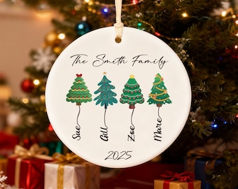 May include: A white ceramic Christmas ornament with the text "The Smith Family" and four illustrated Christmas trees. Each tree has a name below it: Sue, Gill, Zoe, and Mare. The year 2025 is printed at the bottom.