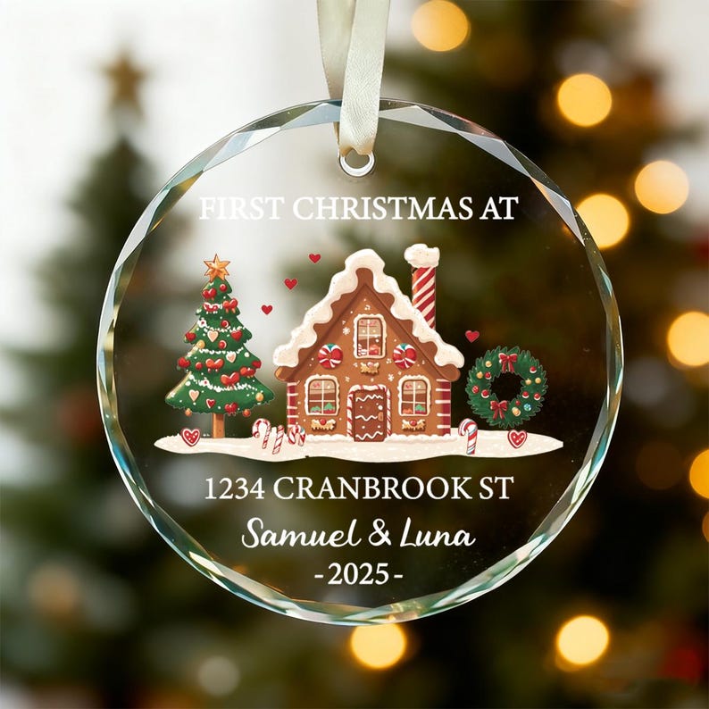 K&ouml;nnte beinhalten: Ein klarer, facettierter Weihnachtsbaumschmuck aus Glas mit einem festlichen Lebkuchenhaus- und Weihnachtsbaumdesign. Der Schmuck enth&auml;lt den Text "FIRST CHRISTMAS AT", Adresse, Namen und das Jahr 2025. Ein wei&szlig;es Band ist zum Aufh&auml;ngen befestigt.