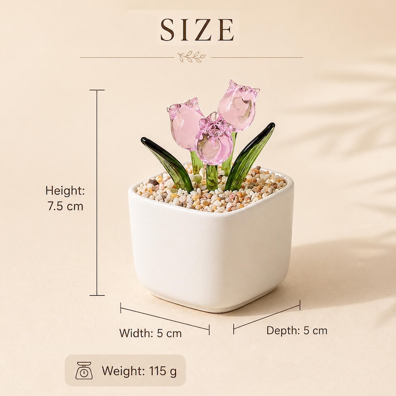 Op de afbeelding: Een kleine, witte vierkante keramische pot met drie roze glazen tulpen en groene bladeren. De pot is gevuld met kleine kiezelstenen. De hoogte is 7,5 cm, breedte en diepte zijn 5 cm, en het gewicht is 115 g. Het woord "SIZE" staat bovenaan.