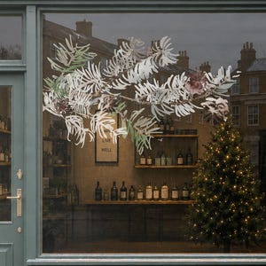 Può includere: Una vetrina con facciata verde scuro e la scritta Wild & Rooted ORGANIC LIVING. All'interno si vedono scaffali con bottiglie e un albero di Natale illuminato. Un cartello sul marciapiede riporta ORGANIC LOCAL SUSTAINABLE ETHICAL.