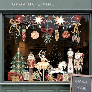 Op de afbeelding: Een winkelpui met een donkergroene gevel en het opschrift Wild & Rooted Organic Living. De etalage bevat kerststickers zoals een kerstboom, notenkraker, ballerina, hobbelpaard en klok, naast een stoepbord met de tekst Organic Local Sustainable Ethical.