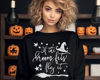 Op de afbeelding: Zwart sweatshirt met de witte tekst "If the broom fits fly it", een heksenhoed, sterren en een bezem-afbeelding. Een Halloween-thema.