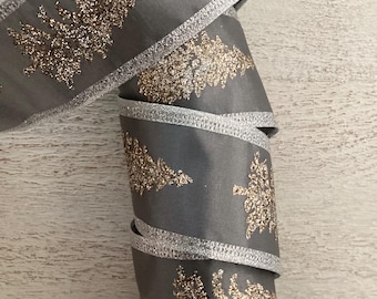 May include: A roll of gray ribbon with silver trim and gold glitter Christmas tree designs. The ribbon is tightly coiled, showcasing the festive pattern. Ideal for holiday crafts and gift wrapping.