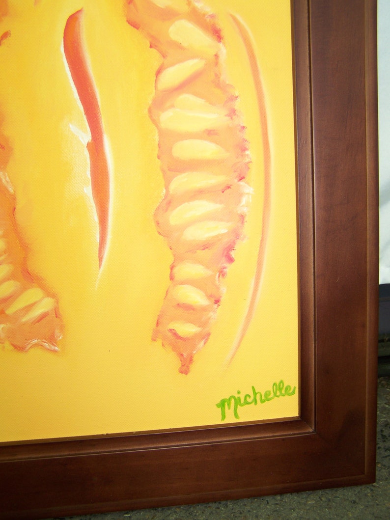 May include: A yellow canvas painting with a pink and yellow abstract design. The painting is framed in a dark brown wood frame. The artist's signature, "Michelle", is written in green paint in the bottom right corner.