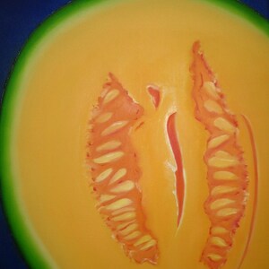 May include: A close-up of a halved cantaloupe melon with a bright orange flesh and a green rind. The melon has a distinct, symmetrical pattern of seeds in the center.