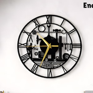 May include: Black metal wall clock with a gear and tool design, featuring Roman numerals and gold clock hands. The clock is mounted on a white wall in a workshop setting. The text "Enchantingspace" is at the top right.