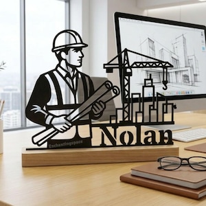 May include: Black laser-cut wooden desk decor featuring an architect holding blueprints, with the name "Nolan" below. The design includes a construction site silhouette and the text "Enchantingspace". The decor sits on a wooden base.