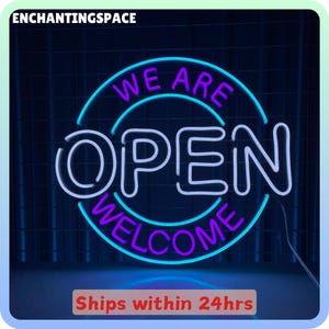 Pode incluir: Letreiro de néon com a palavra "OPEN" em branco, rodeado por um círculo azul com "WE ARE" e "WELCOME" em roxo. Num fundo azul escuro. O texto "ENCHANTINGSPACE" está no topo.