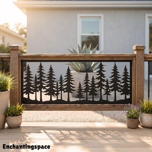 May include: A rectangular black metal panel featuring a laser-cut silhouette of a dense pine forest. The panel is framed by a wooden railing structure. The text "Enchantingspace" is printed in black at the bottom left corner of the image.