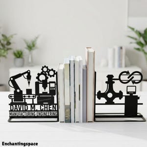 Może przedstawiać: Para czarnych metalowych podpórek do książek z wzorami produkcji przemysłowej. Lewy element przedstawia ramię robota, koła zębate i napis "DAVID M. CHEN MANUFACTURING ENGINEERING". Prawy element pokazuje zawór i monitor komputerowy.