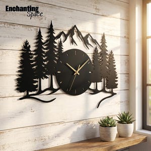 May include: A black metal wall clock featuring a silhouette of pine trees and mountain peaks. The circular clock face has thin gold hands and simple gold hour markers. The text Enchanting Space is visible in the upper left corner of the image.