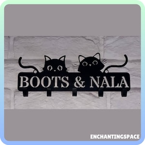 May include: Black metal key holder with two cat silhouettes and the text "BOOTS & NALA". The key holder has five hooks.