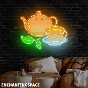 May include: Neon sign depicting a teapot and teacup with a leaf, in shades of orange, yellow, green, and blue. The sign is mounted on a black brick wall. The text "ENCHANTINGSPACE" is at the bottom.