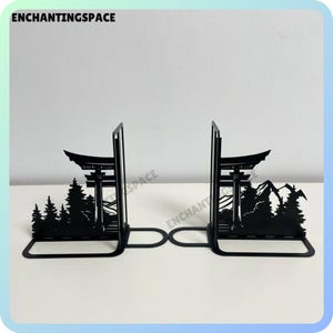 Könnte beinhalten: Schwarze Metall-Buchstützen mit einer Silhouette eines japanischen Tempeltors und einer Berglandschaft. Die Buchstützen sind so konzipiert, dass sie Bücher aufrecht auf einem Regal oder Schreibtisch halten.