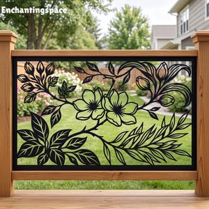 May include: A black metal decorative railing panel featuring a laser-cut floral design with blooming flowers, buds, and detailed leaves. The rectangular panel is framed by natural light-colored wooden posts and rails, set against a green lawn.