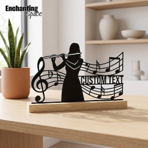 Puede incluir: Una silueta de metal negro de una persona tocando la flauta, integrada con pentagramas, notas musicales, una clave de sol y un recorte rectangular con la etiqueta CUSTOM TEXT, montada sobre una base de madera de color claro.
