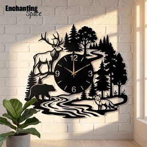 May include: A black wall clock featuring a forest scene with a deer, a bear, and a fox. The clock face is circular with gold hands and numbers 3, 6, 9, and 12. The silhouette design includes pine trees and a winding river.