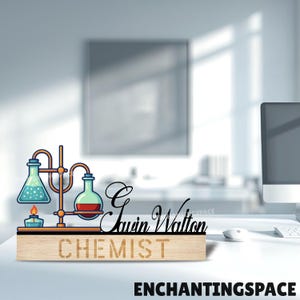 Può includere: Un cartello da scrivania in legno con il nome "Gavin Walton" e la parola "CHEMIST" incisa. Il cartello presenta un'illustrazione stilizzata di attrezzature da laboratorio, tra cui beute e un bruciatore. Il cartello è su una scrivania bianca.