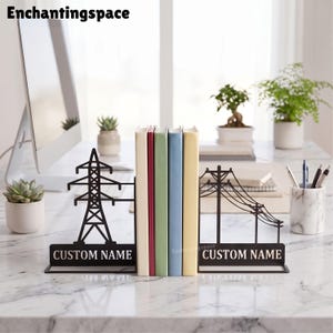 May include: A pair of black metal bookends featuring a silhouette of an electrical transmission tower on one side and a utility pole with power lines on the other. Each base includes a rectangular plate with the text CUSTOM NAME in white.