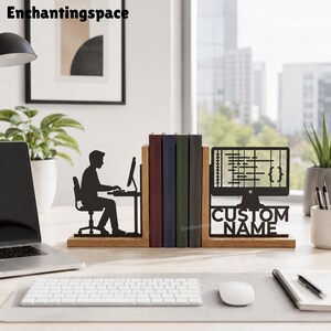 May include: A wooden bookend set featuring a black metal silhouette of a person sitting at a computer desk on the left and a black metal computer monitor displaying code with the text CUSTOM NAME underneath on the right side.