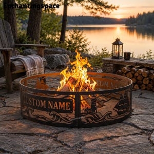 May include: A circular metal fire pit ring featuring cut-out silhouettes of a lighthouse, sailing ships, and ocean waves. The side of the ring includes a rectangular panel with the text CUSTOM NAME. A bright orange fire burns inside the ring.