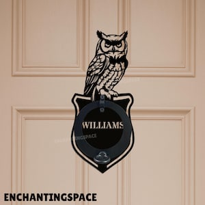 以下が含まれることがあります： 黒い金属製のドアノッカー。詳細なフクロウが盾型のプレートの上に止まっています。 プレートには「WILLIAMS」という名前とハンドルが付いた円形のエリアがあります。 テキスト「ENCHANTINGSPACE」が一番下にあります。